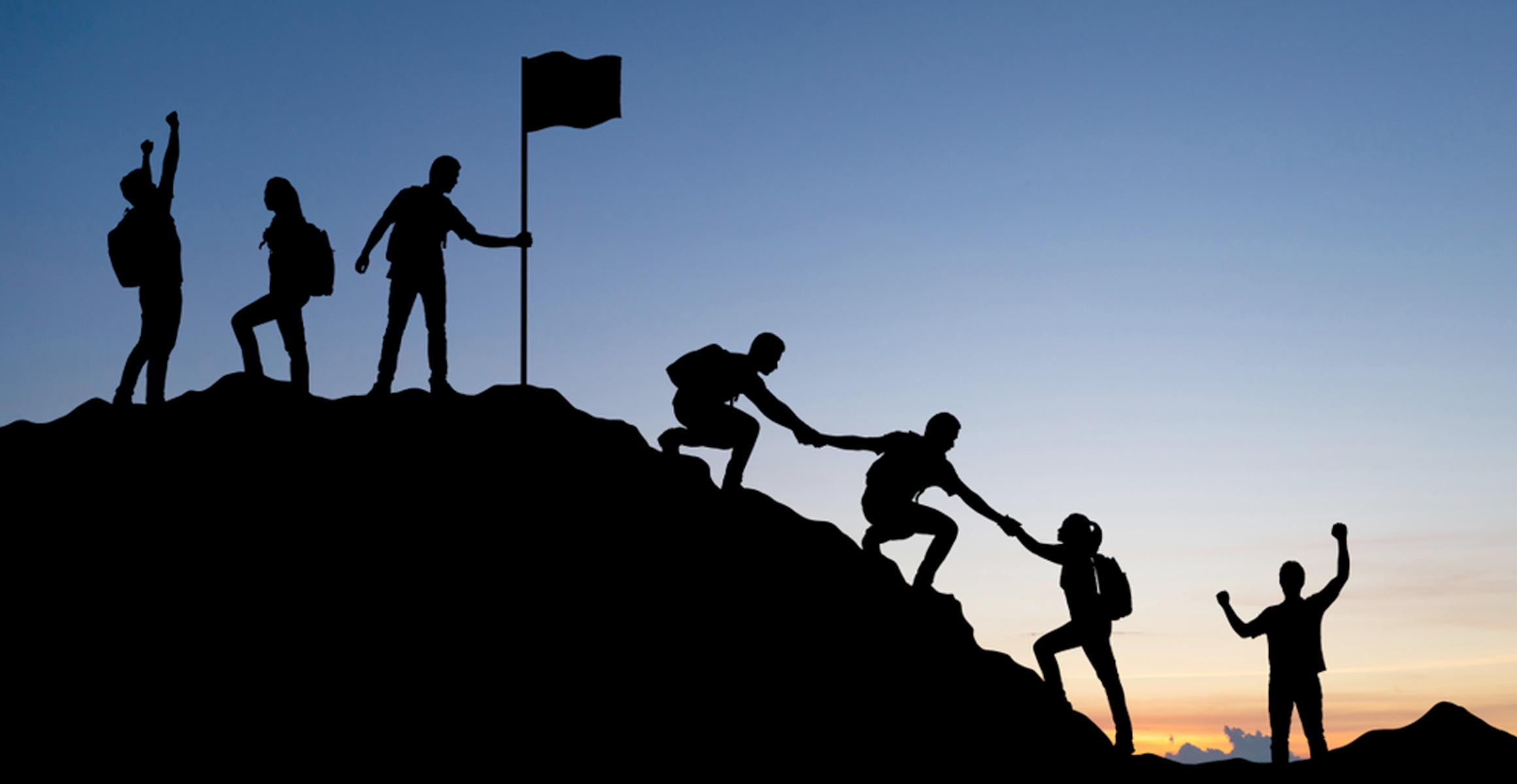 Silhouettes climbing to a summit at sunset